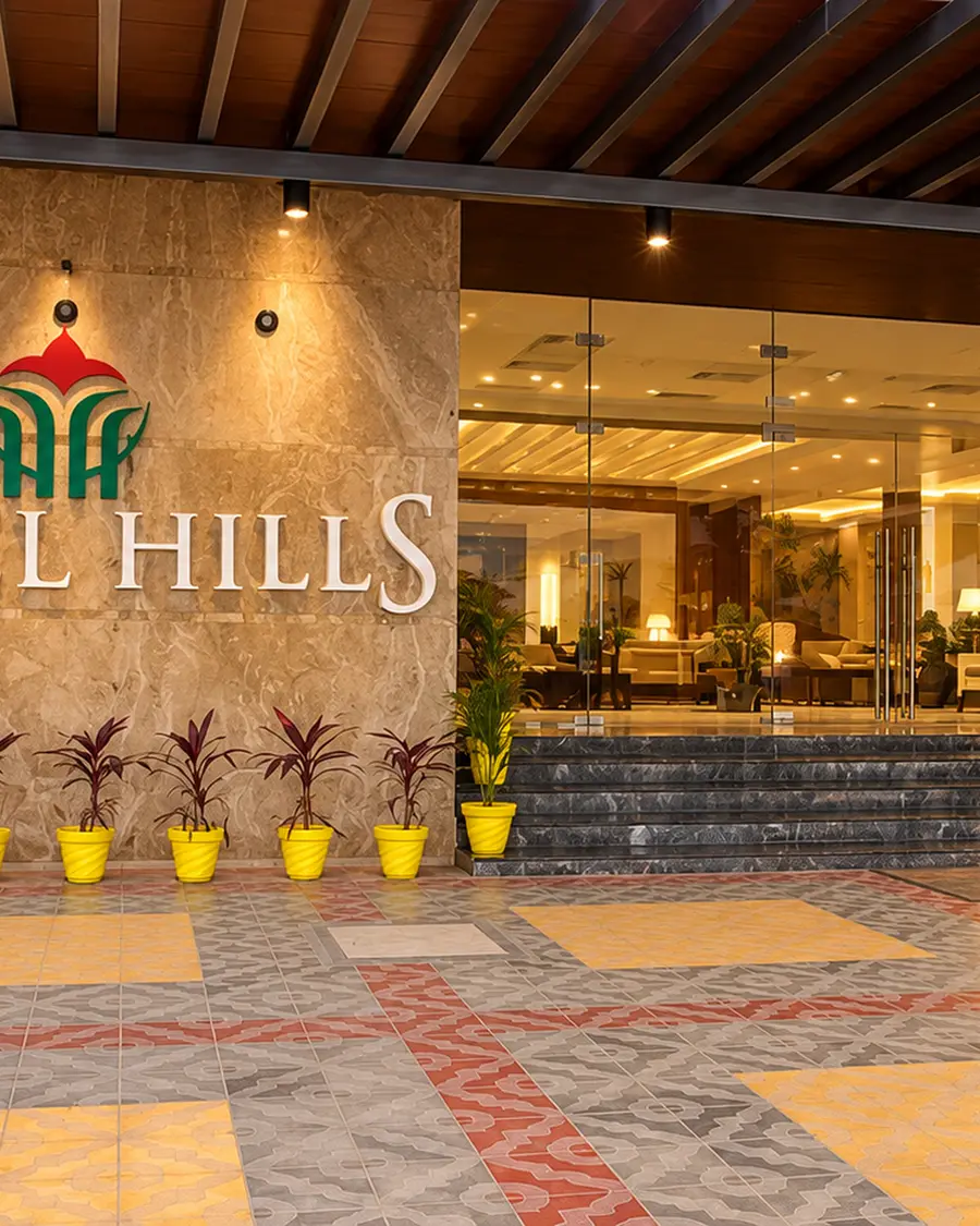 The entrance of Hotel Hills Tirupattur, the sign lit under a pergola