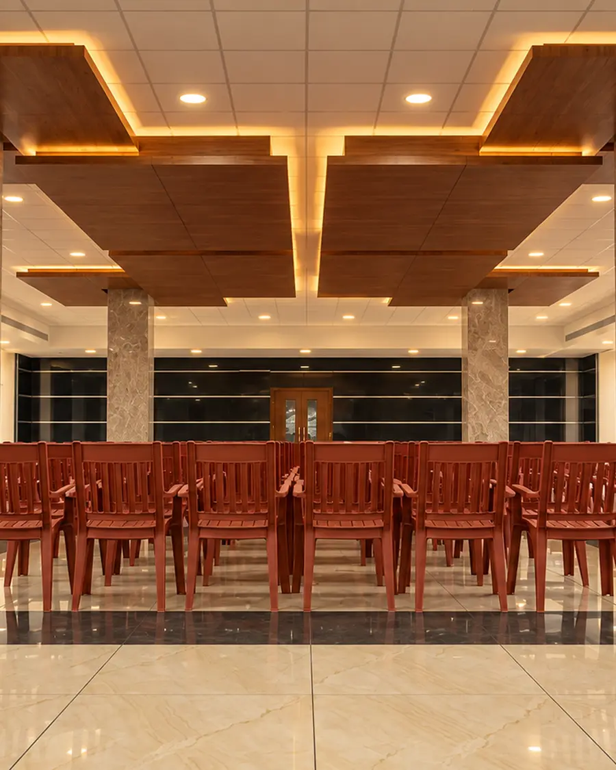 The banquet hall at Hotel Hills Tirupattur, set with rows of wooden chairs